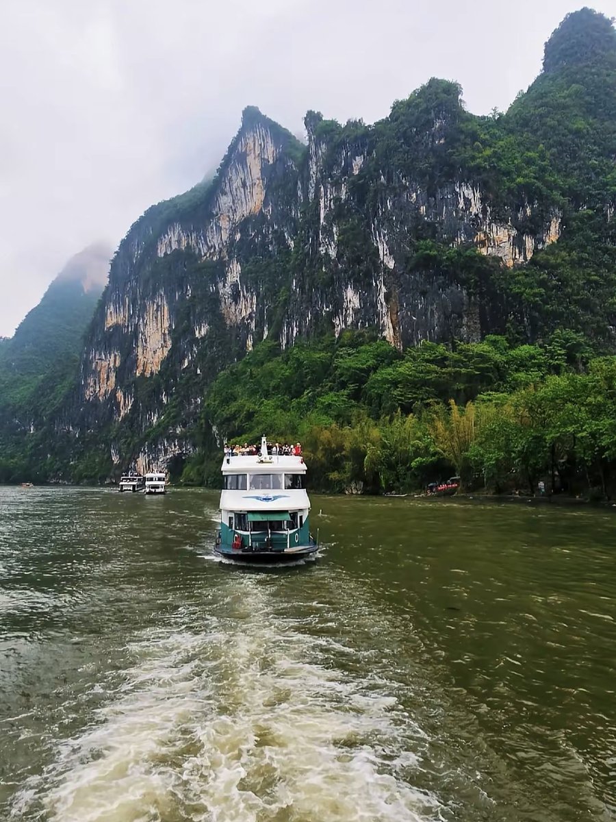 Barco navegando por el río Li junto a acantilados de karst